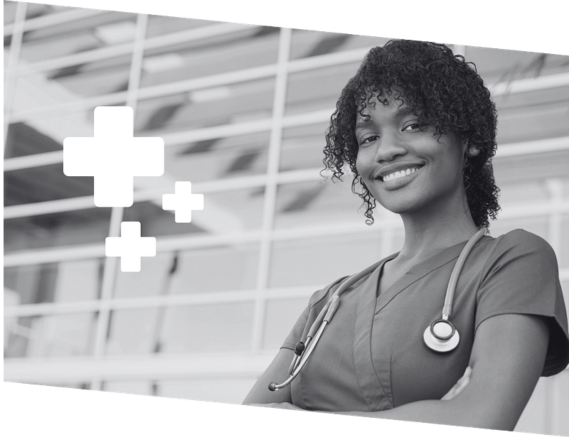 Smiling healthcare professional with stethoscope stands in front of a building.