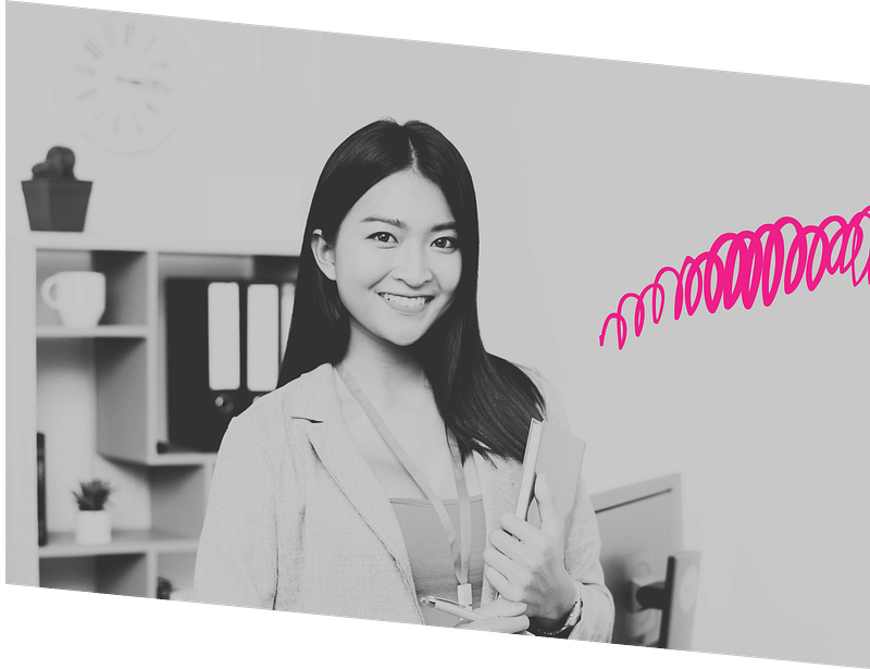 Smiling person holding books, wearing a lanyard, in an office setting with shelves, binders, clock, plant, and pink swirl on the side.